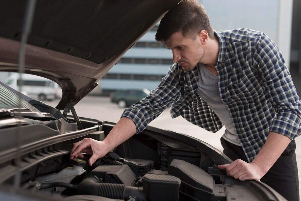 un homme inspecte le moteur d’une voiture.